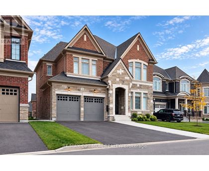 A large, two-story house with a brick facade and a black car parked in the driveway.