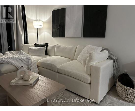 A white couch with a grey throw blanket on it.