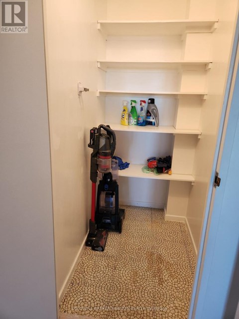 A vacuum cleaner is on the floor of a room with white shelves.