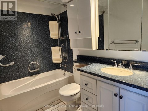 A bathroom with a black speckled wall and a white bathtub.