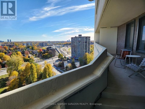 A balcony overlooks a cityscape with trees in autumn colors.