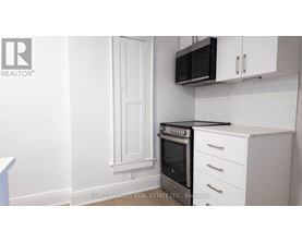 A kitchen with white cabinets and a black microwave.
