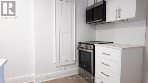 A kitchen with white cabinets and a black microwave.
