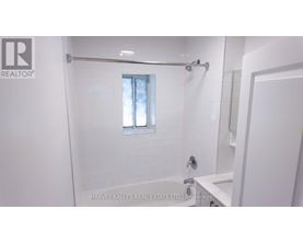 A white bathroom with a window and a shower.