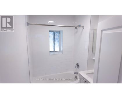 A white bathroom with a window and a shower.