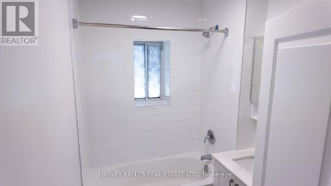 A white bathroom with a window and a shower.