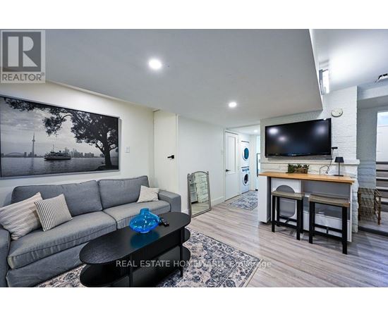 A living room with a grey couch and a coffee table in front of a large painting.