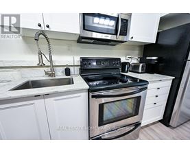 A modern kitchen with white cabinets and stainless steel appliances.