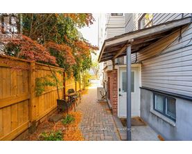 A narrow alley with a wooden fence on the left and a brick building on the right.