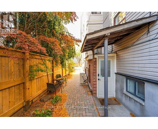 A narrow alley with a wooden fence on the left and a brick building on the right.
