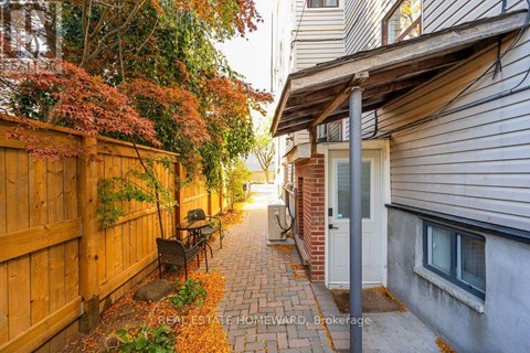 A narrow alley with a wooden fence on the left and a brick building on the right.