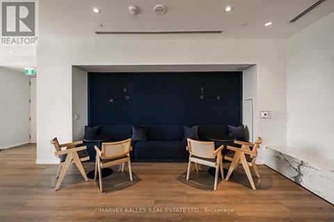 A living room with a dark blue couch and wooden chairs.