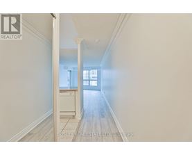 A hallway with a doorway leading to a room with a window.