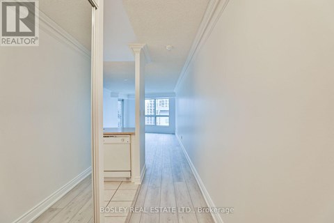 A hallway with a doorway leading to a room with a window.