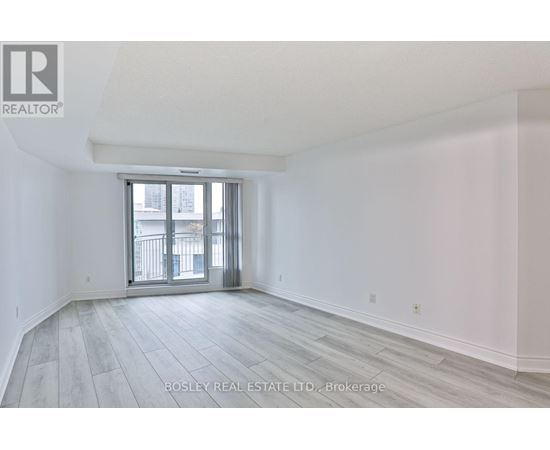 A spacious room with a sliding glass door leading to a balcony.
