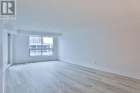 A spacious room with a large window and wooden flooring.
