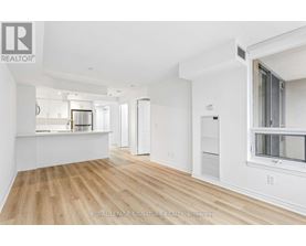 A spacious, empty room with wooden floors and white walls.
