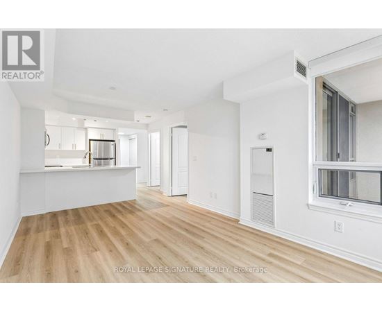 A spacious, empty room with wooden floors and white walls.