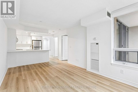 A spacious, empty room with wooden floors and white walls.