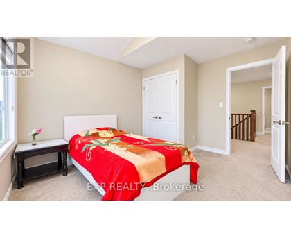 A bedroom with a bed covered in a red and gold comforter.