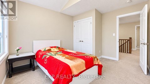 A bedroom with a bed covered in a red and gold comforter.