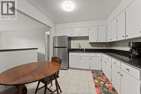 A kitchen with white cabinets and a wooden table.