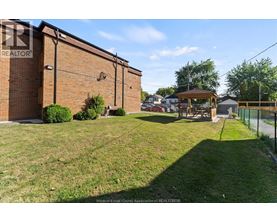 A grassy area in front of a brick building with a gazebo in the background.