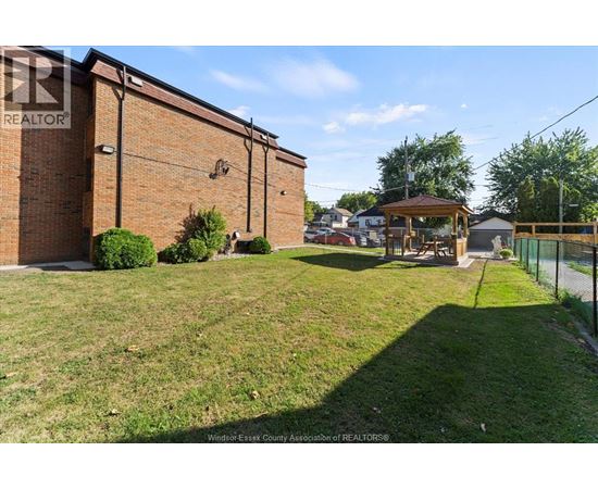 A grassy area in front of a brick building with a gazebo in the background.