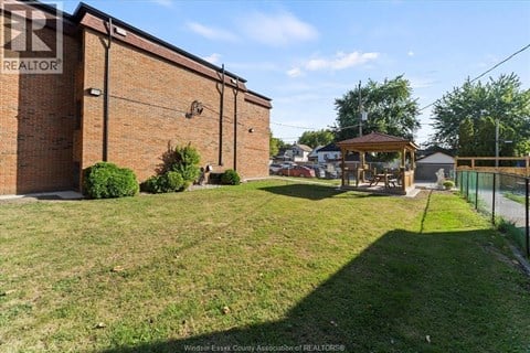 A grassy area in front of a brick building with a gazebo in the background.