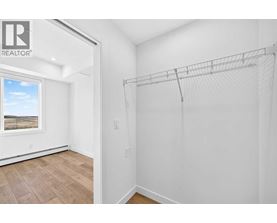 A white bedroom with a large window and a wooden floor.