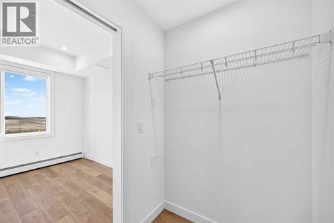 A white bedroom with a large window and a wooden floor.