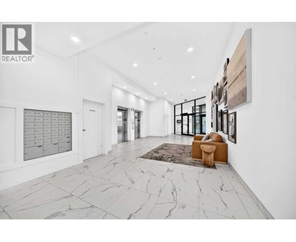A spacious hallway with marble flooring and a rug.