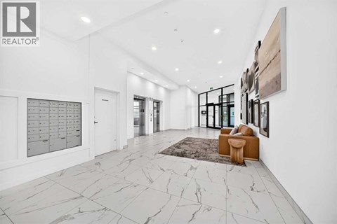 A spacious hallway with marble flooring and a rug.