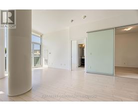 A spacious room with a white floor and a glass door leading to another room.