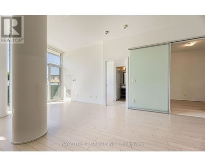 A spacious room with a white floor and a glass door leading to another room.