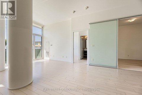 A spacious room with a white floor and a glass door leading to another room.