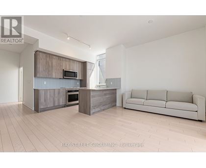 A modern kitchen with a microwave above the oven and a couch in the living room.
