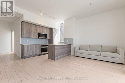 A modern kitchen with a microwave above the oven and a couch in the living room.