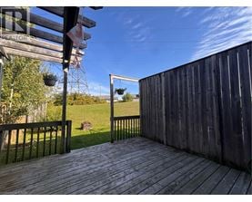 A wooden deck with a metal railing and a view of a grassy field.