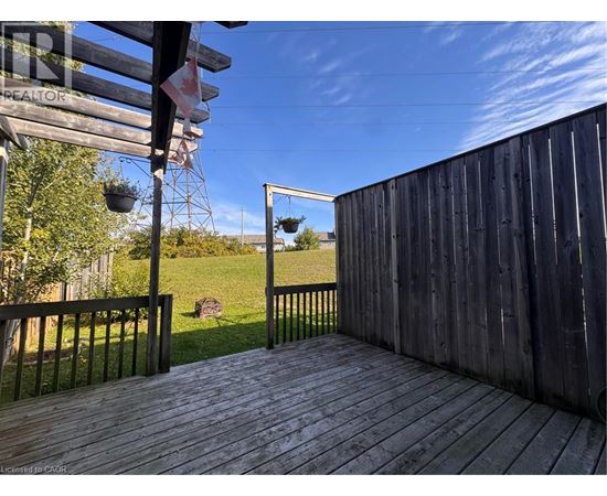 A wooden deck with a metal railing and a view of a grassy field.