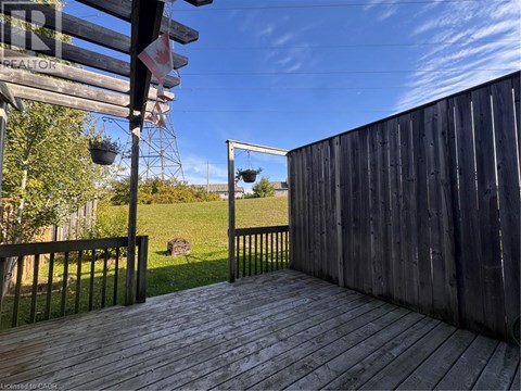 A wooden deck with a metal railing and a view of a grassy field.