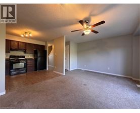A living room with a carpeted floor and a ceiling fan.