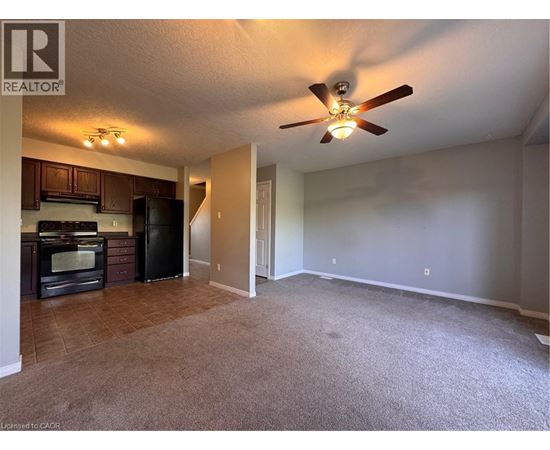 A living room with a carpeted floor and a ceiling fan.