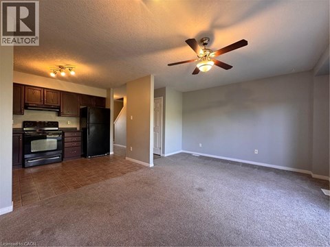 A living room with a carpeted floor and a ceiling fan.