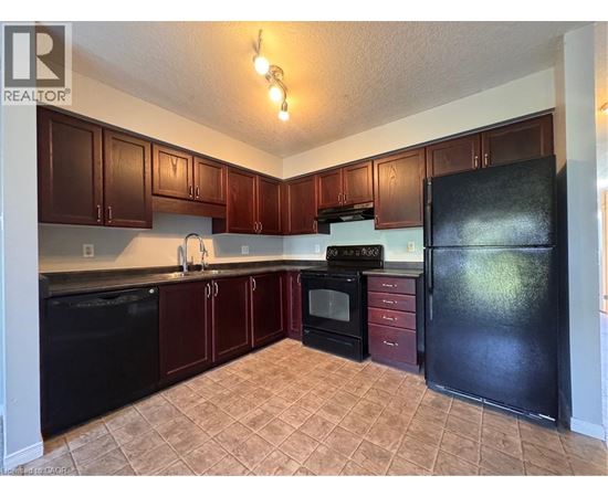 A kitchen with brown cabinets and black appliances.