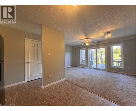 A spacious room with a ceiling fan and sliding glass doors leading to a deck.