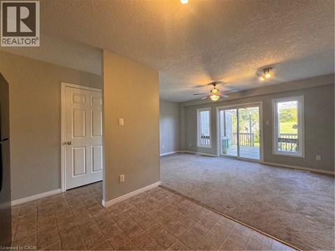 A spacious room with a ceiling fan and sliding glass doors leading to a deck.
