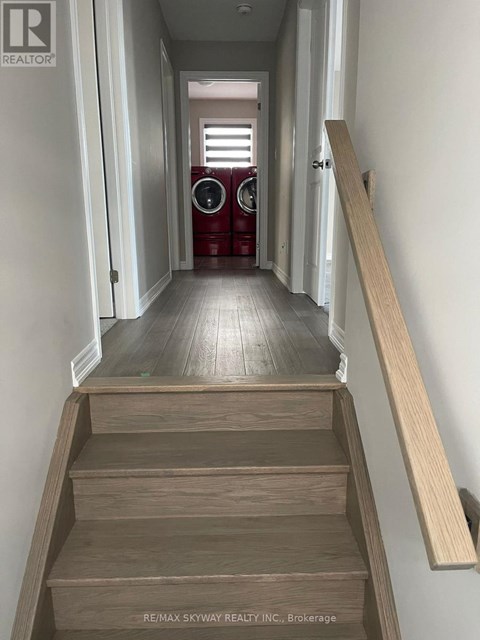 A hallway with a wooden staircase leading to a door.