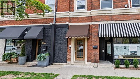 A brick building with a black awning and a sign that says MA on it.