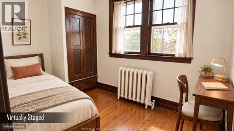 A bedroom with a bed, desk, chair, and window.